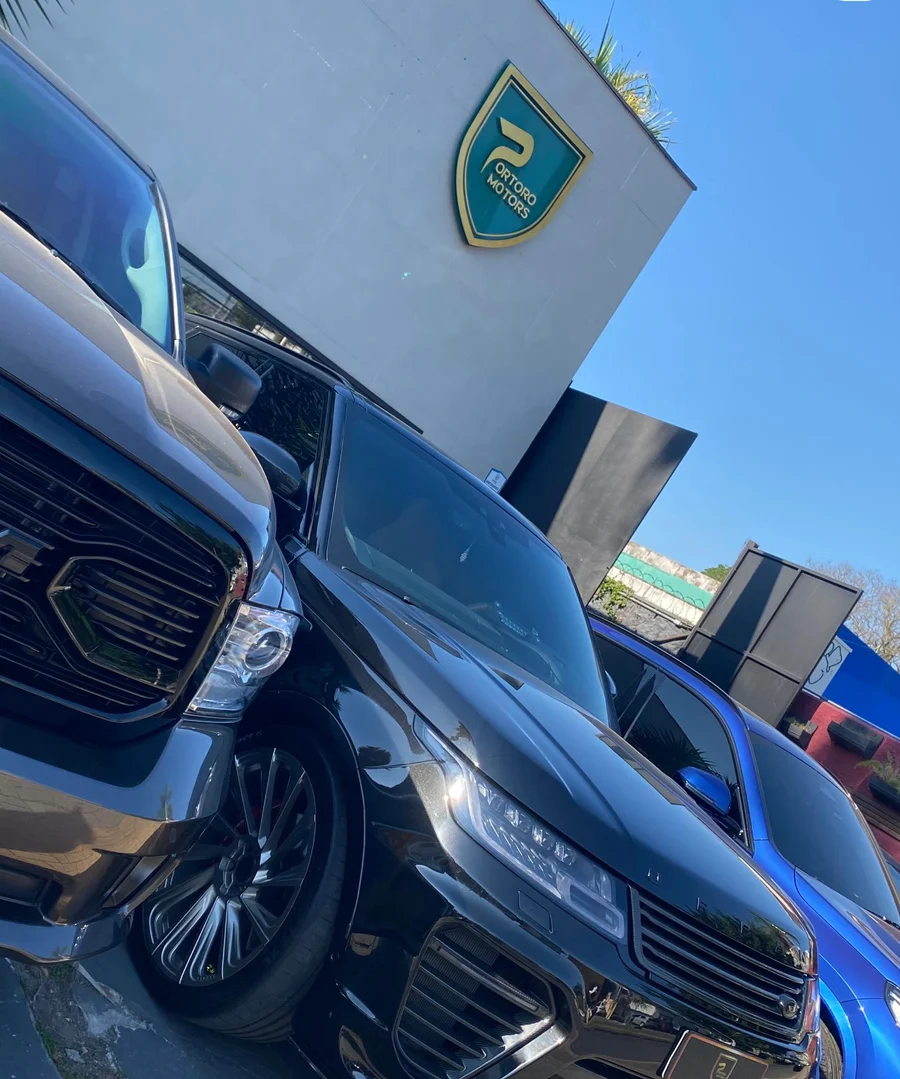 Fachada da Portoro Motors, com seu brasão dourado e veículos à frente
